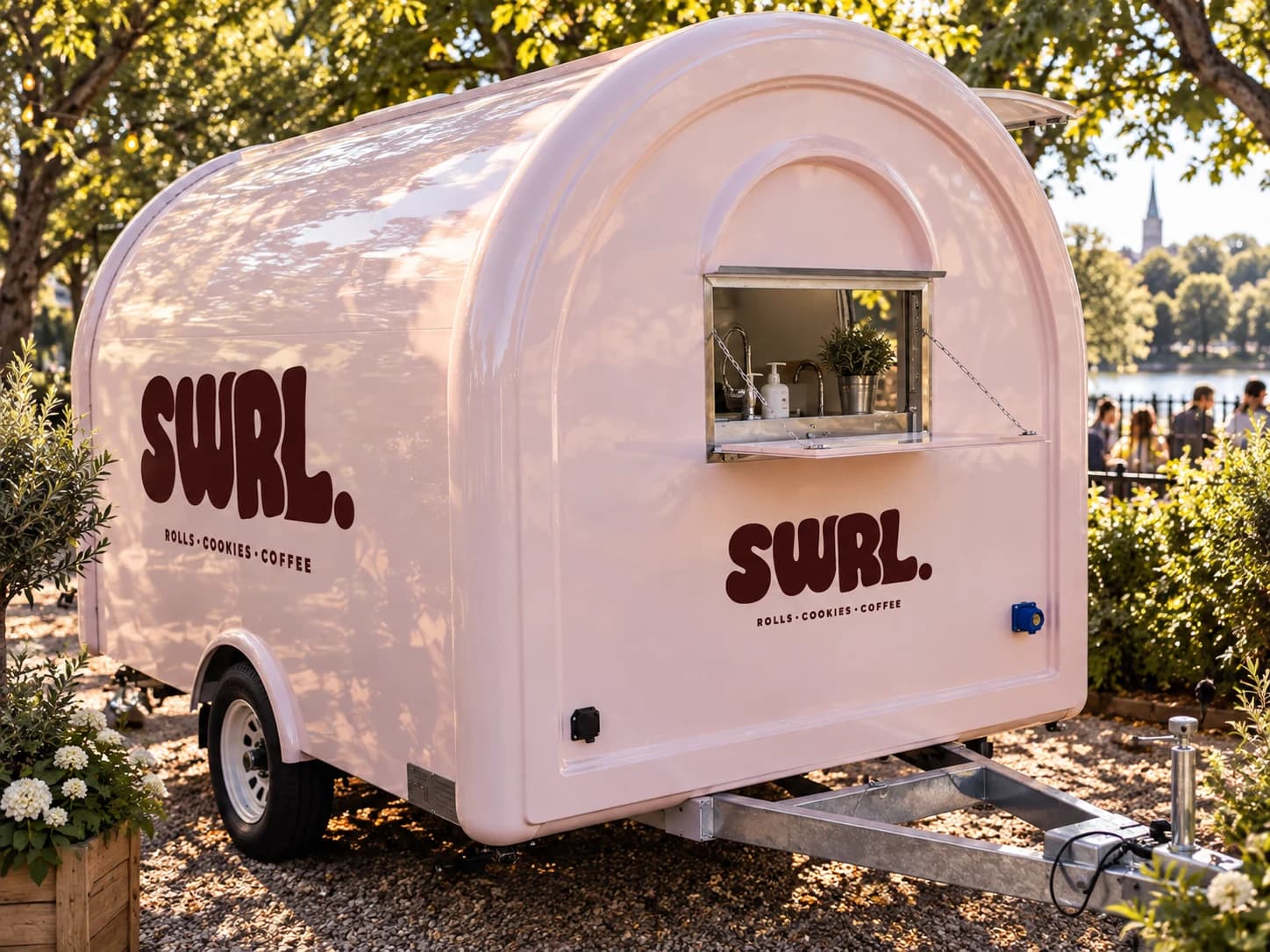 The rounded pink side of the SWRL truck beneath leafy trees
